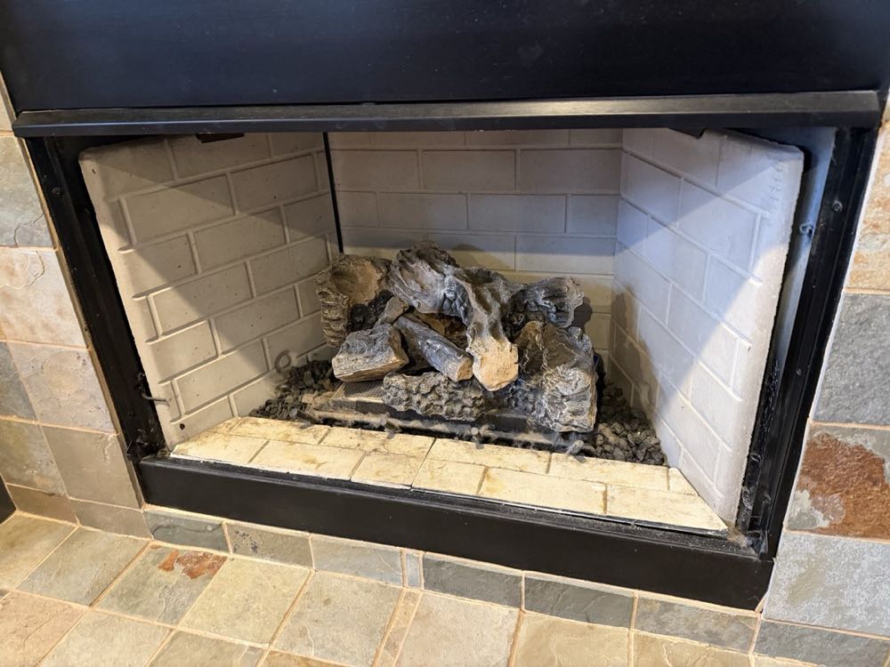 Vented gas log set burning in a masonry fireplace after professional installation in Dallas–Fort Worth