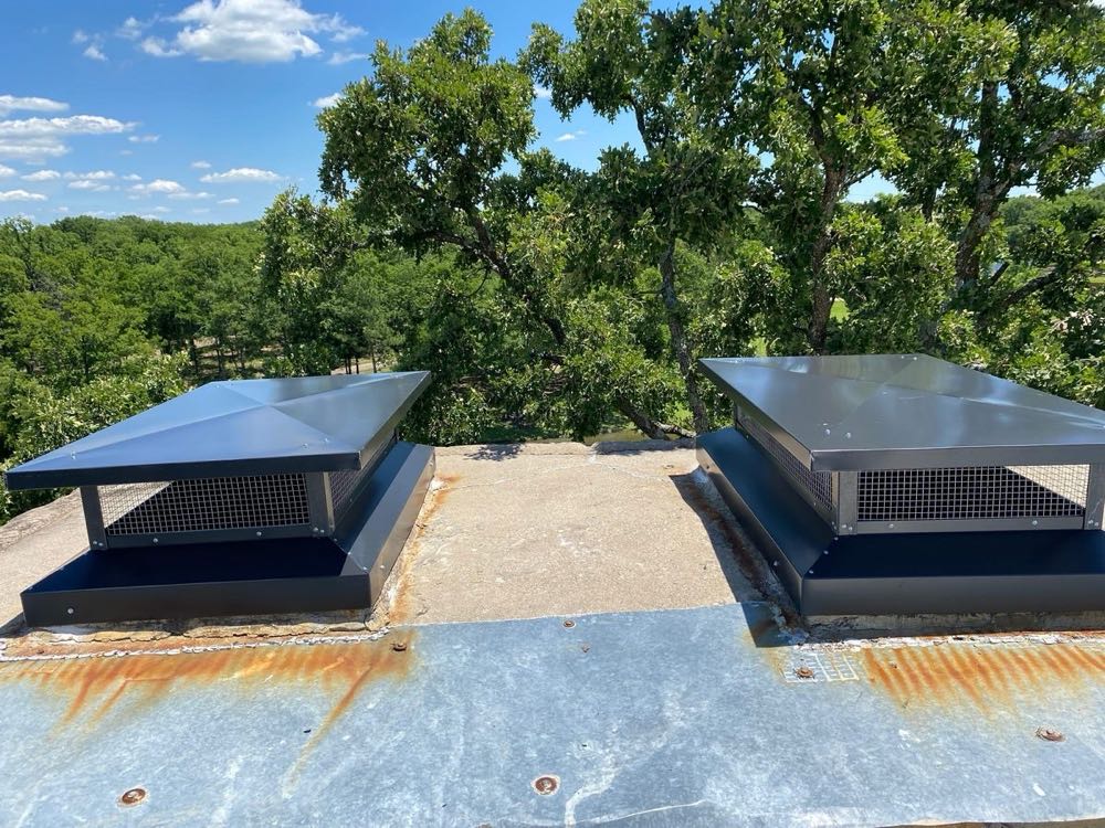 Two capped flues on a Dallas roof after chimney cricket and drainage work